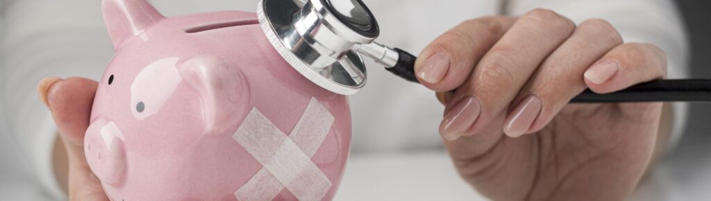 Pessoa segurando um cofre em formato de porquinho rosa com curativos adesivos, enquanto usa um estetoscópio para “verificar” o cofre, simbolizando cuidados com as finanças pessoais ou a saúde da reserva de emergência.