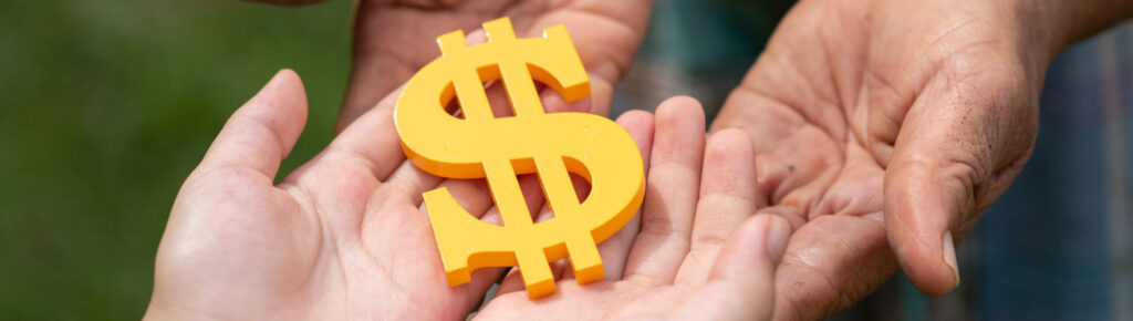Mãos de uma pessoa mais velha entregando um símbolo de cifrão amarelo para mãos mais jovens, representando a transferência de dinheiro ou conhecimento financeiro entre gerações.