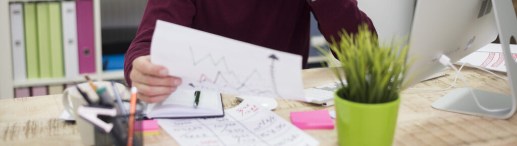Homem de meia-idade analisando gráficos financeiros em escritório, representando análise de dados, planejamento estratégico e tomada de decisão empresarial.