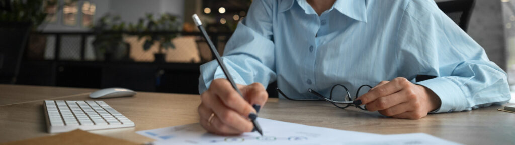 Mulher sorridente analisando gráficos financeiros em escritório moderno.