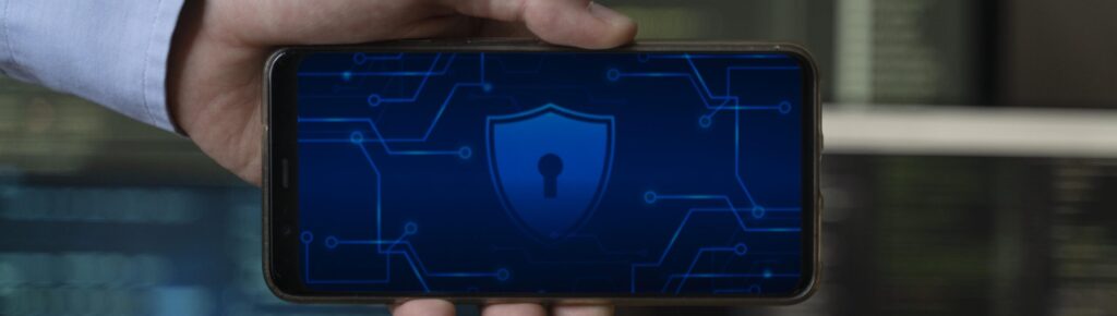 Pessoa segurando um smartphone com ícone de segurança digital na tela, simbolizando proteção de dados, criptografia e segurança em transações financeiras com tecnologia blockchain.
